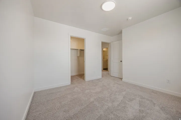 Light gray carpet flooring, white walls, flush mount ceiling light, and white interior doors