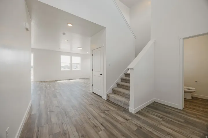 Recessed lighting, wood-finish flooring, white walls, white trim, and a carpeted staircase