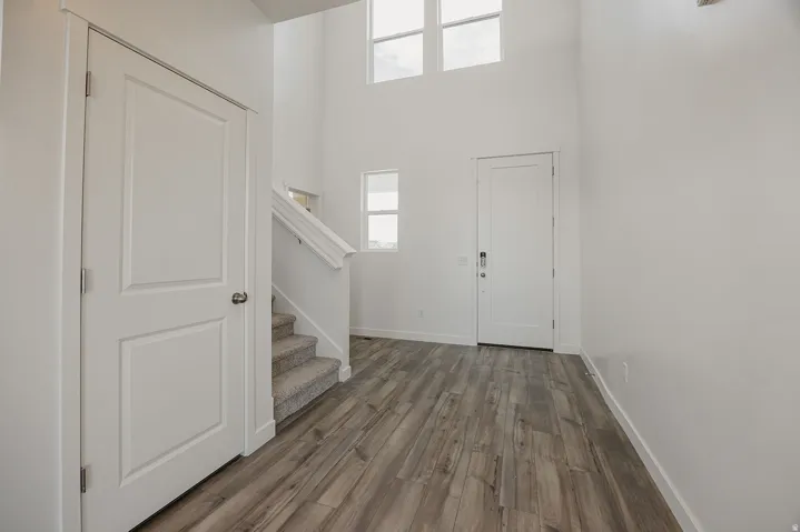 Two-story foyer with high ceilings, wood-finish flooring, and a carpeted staircase with white railings