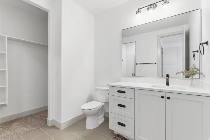 Bathroom with light tile patterned floors, vanity, and a spacious closet