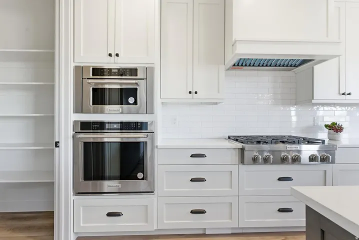 Kitchen with white cabinets, stainless steel appliances, and decorative backsplash