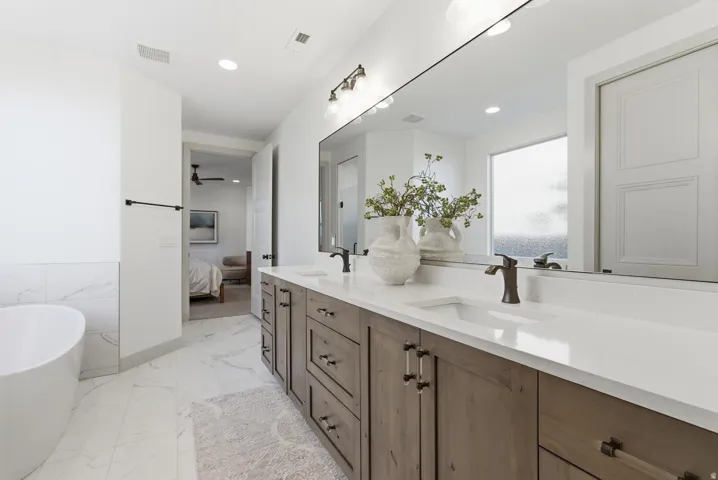 Ensuite bathroom with light marble finish flooring, a freestanding bath, double vanity, recessed lighting, and a ceiling fan