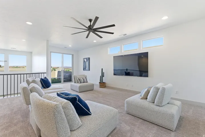 Carpeted living area featuring a ceiling fan and recessed lighting
