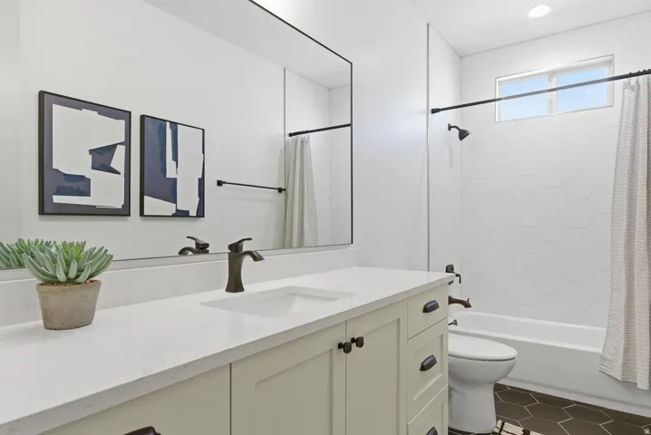 Bathroom featuring vanity, shower / bath combo with shower curtain, and dark tile patterned floors