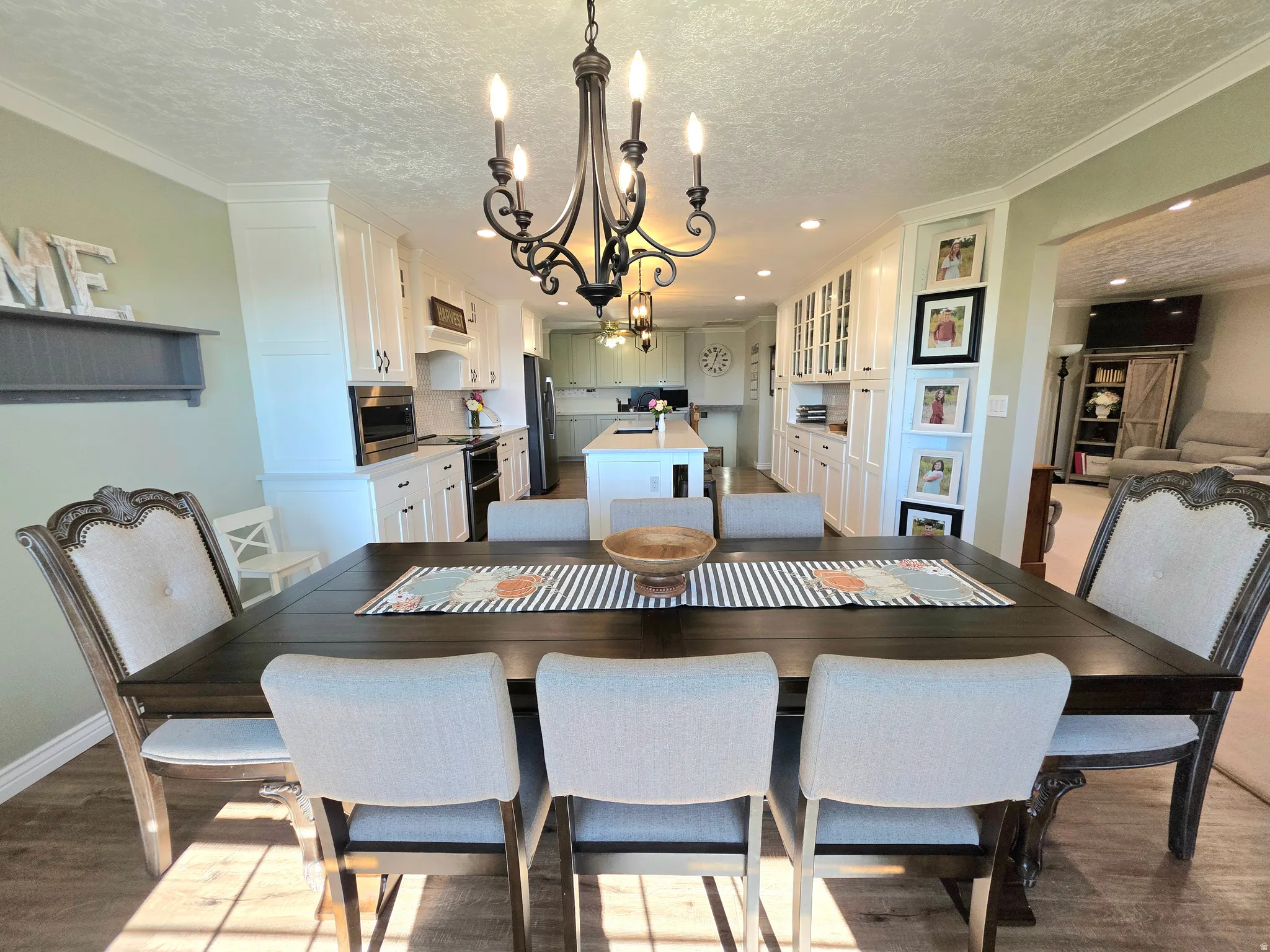 Dining space featuring a chandelier, wood finished floors, ornamental molding, a textured ceiling, and recessed lighting
