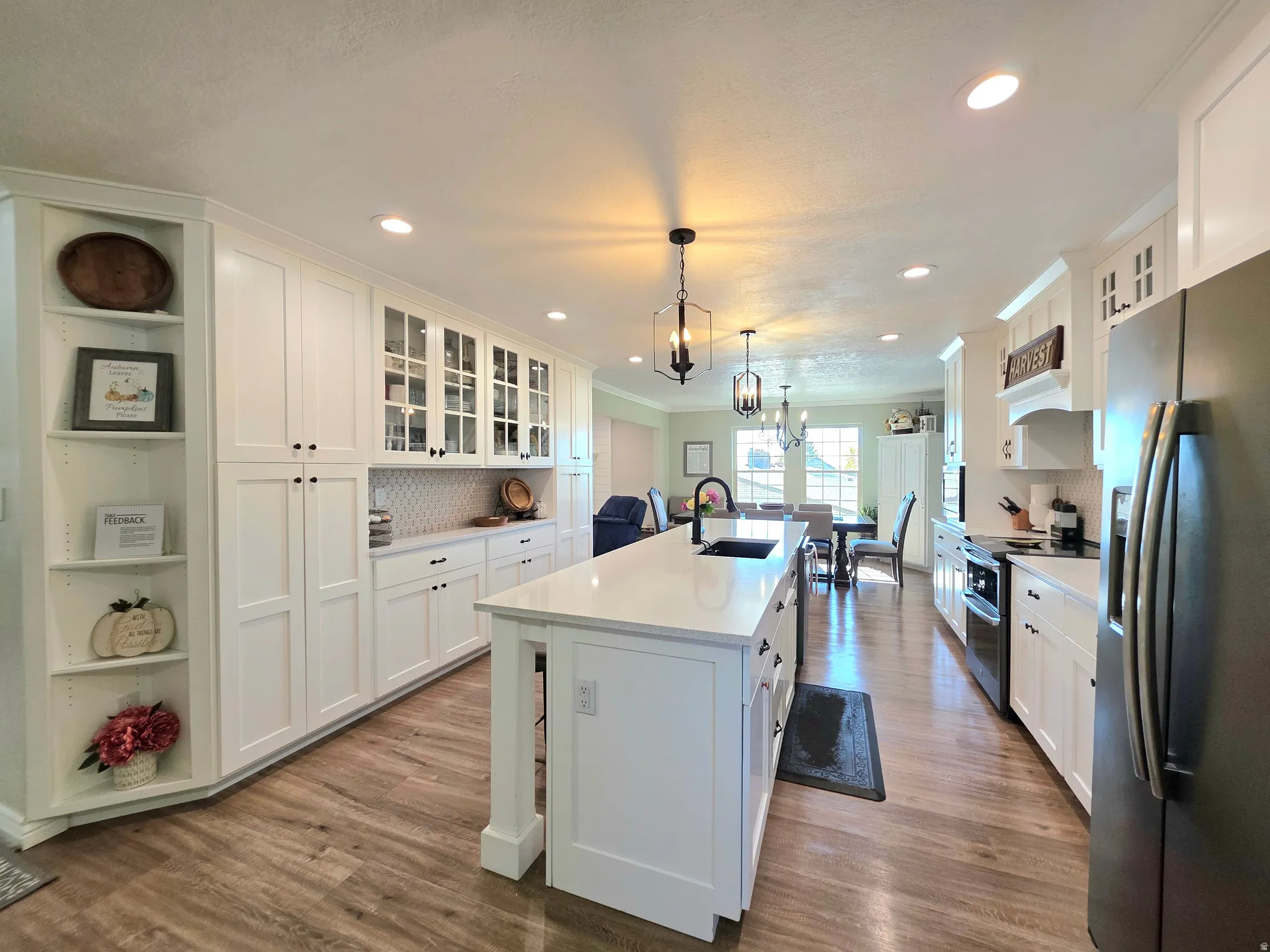 Kitchen featuring glass insert cabinets, fridge with ice dispenser, white cabinets, range with two ovens, and crown molding
