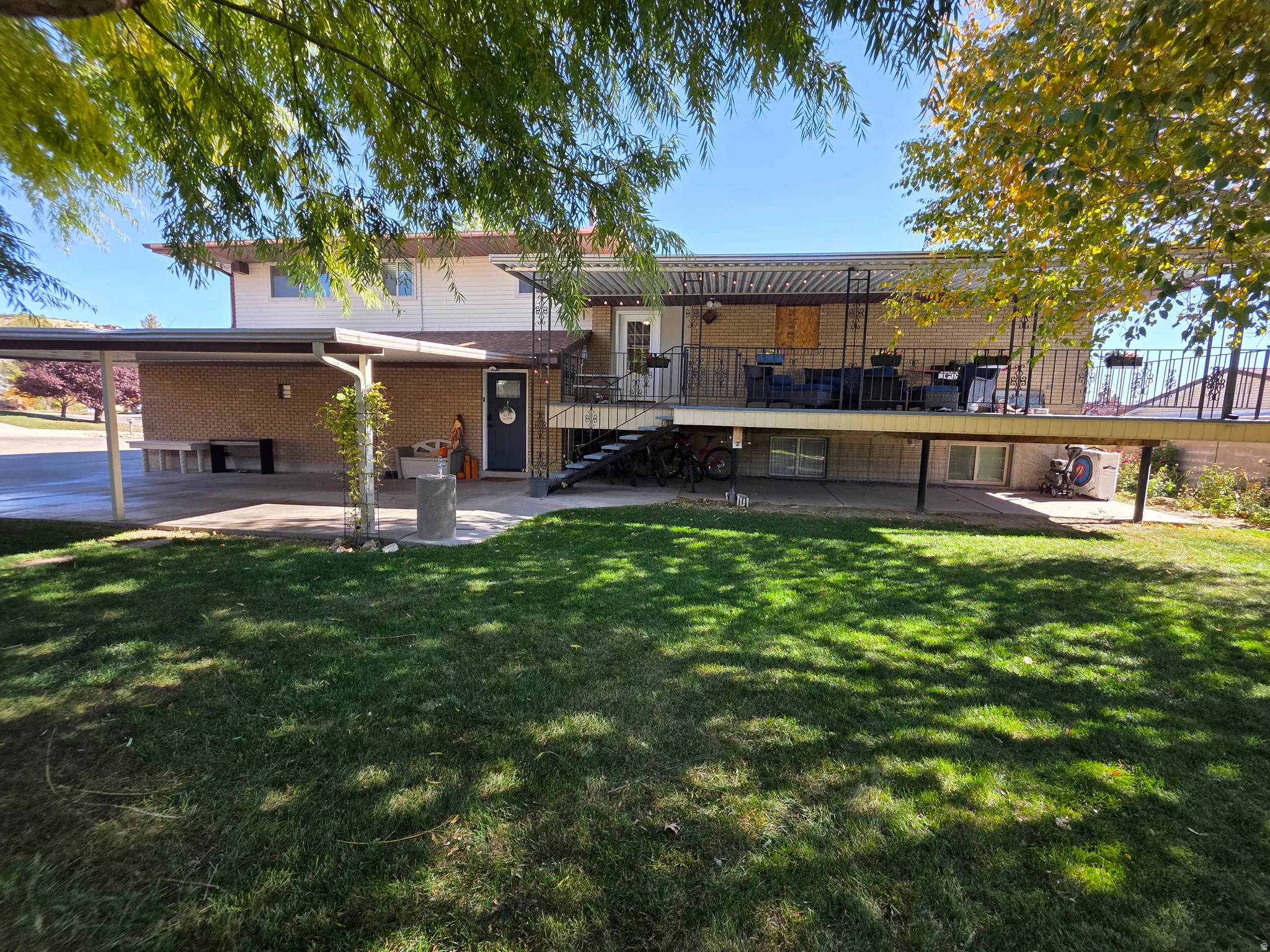 Back of house with stairway, a patio area, a lawn, brick siding, and a wooden deck