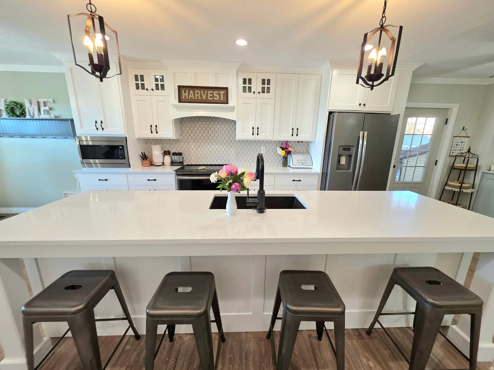 Kitchen with crown molding, a chandelier, stainless steel appliances, decorative backsplash, and a large island with sink