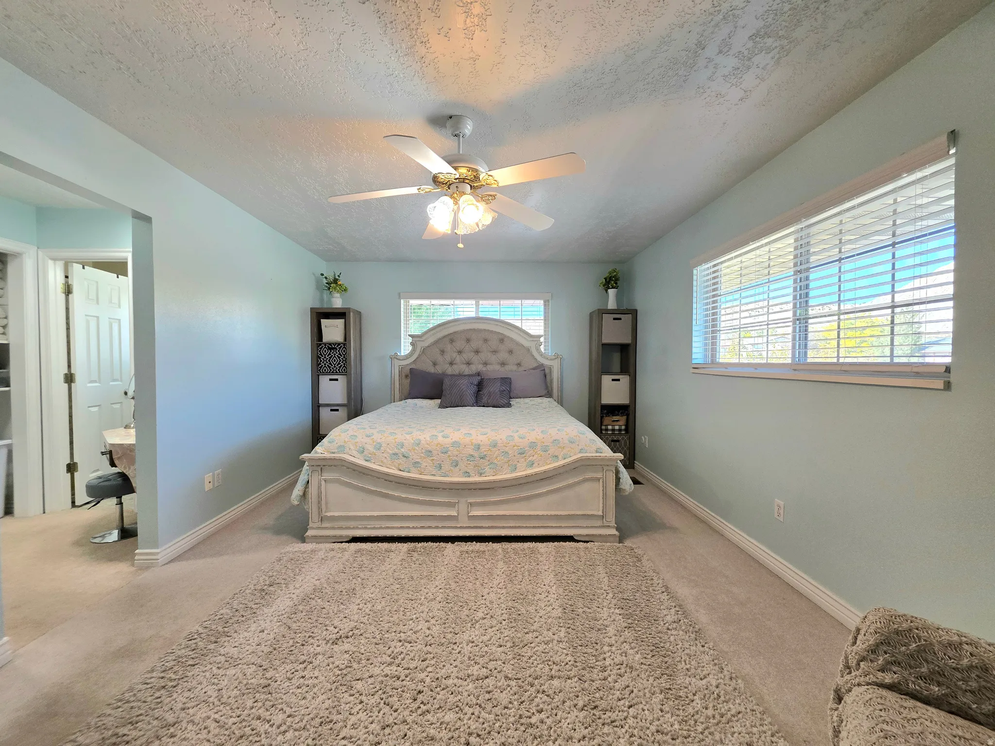 Bedroom featuring light colored carpet, a textured ceiling, and ceiling fan