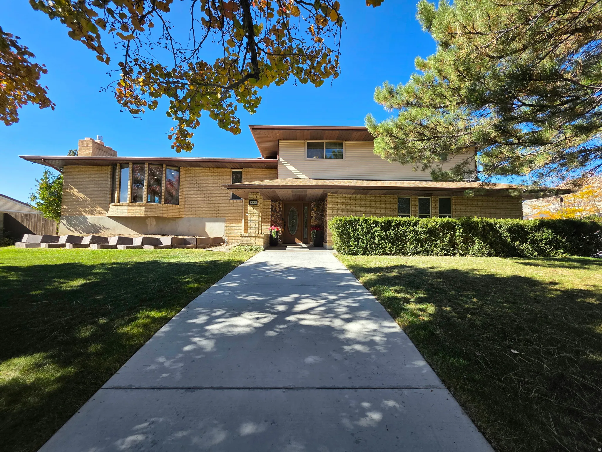 Split level home featuring brick siding, a front lawn, and a chimney