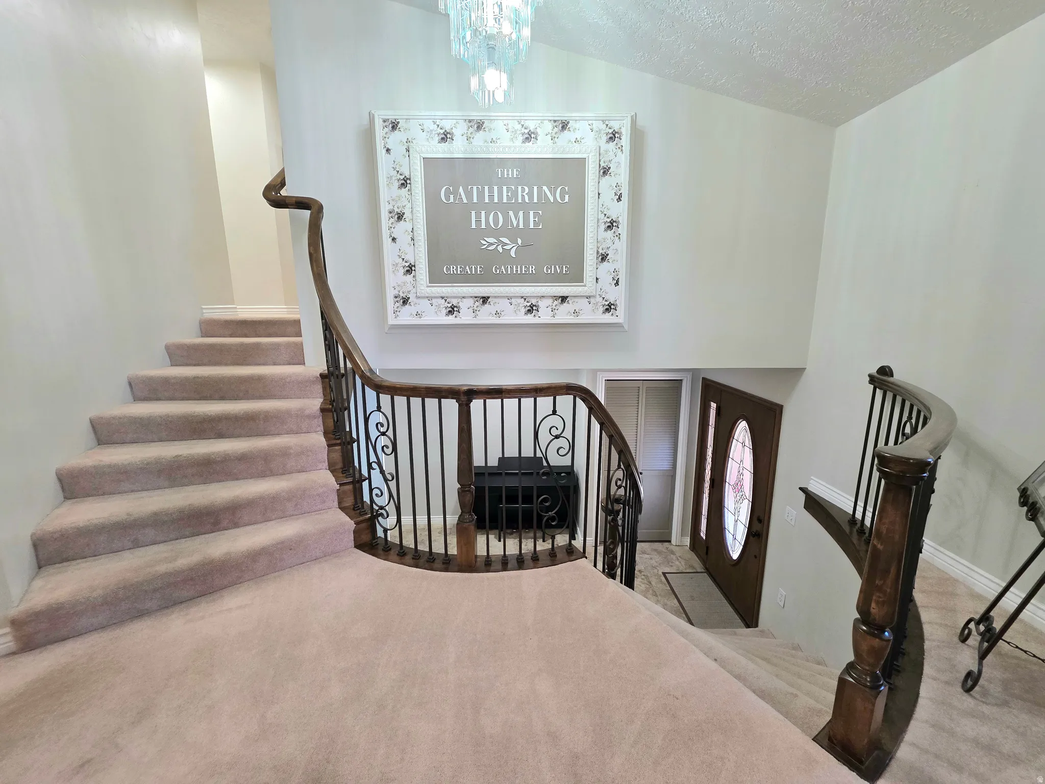 Foyer entrance featuring stairway, a chandelier, carpet flooring, and a textured ceiling