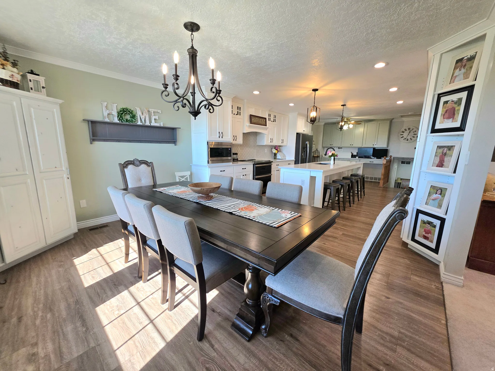 Dining space featuring a chandelier, light wood-type flooring, a textured ceiling, recessed lighting, and crown molding
