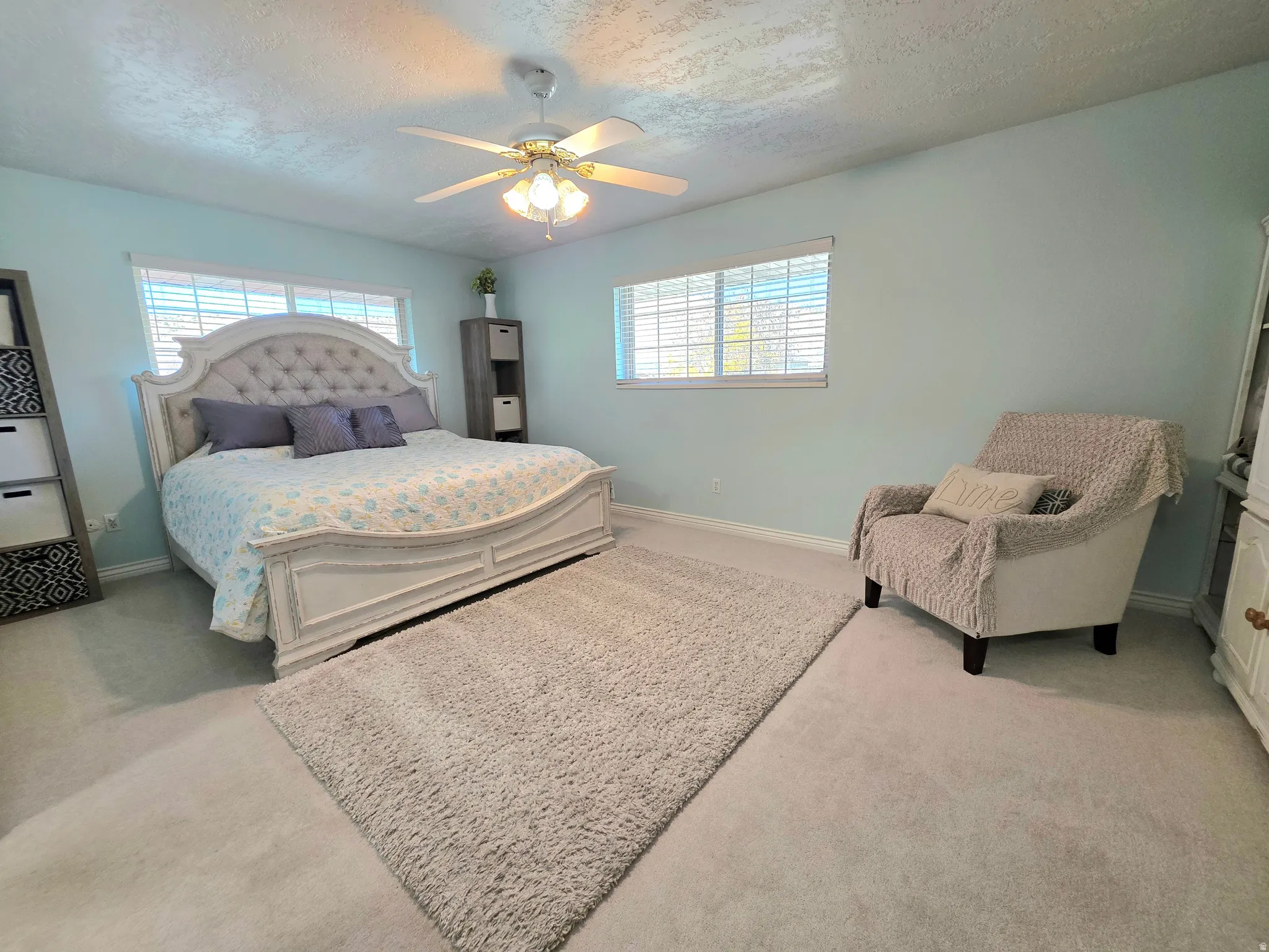 Carpeted bedroom featuring a textured ceiling and a ceiling fan