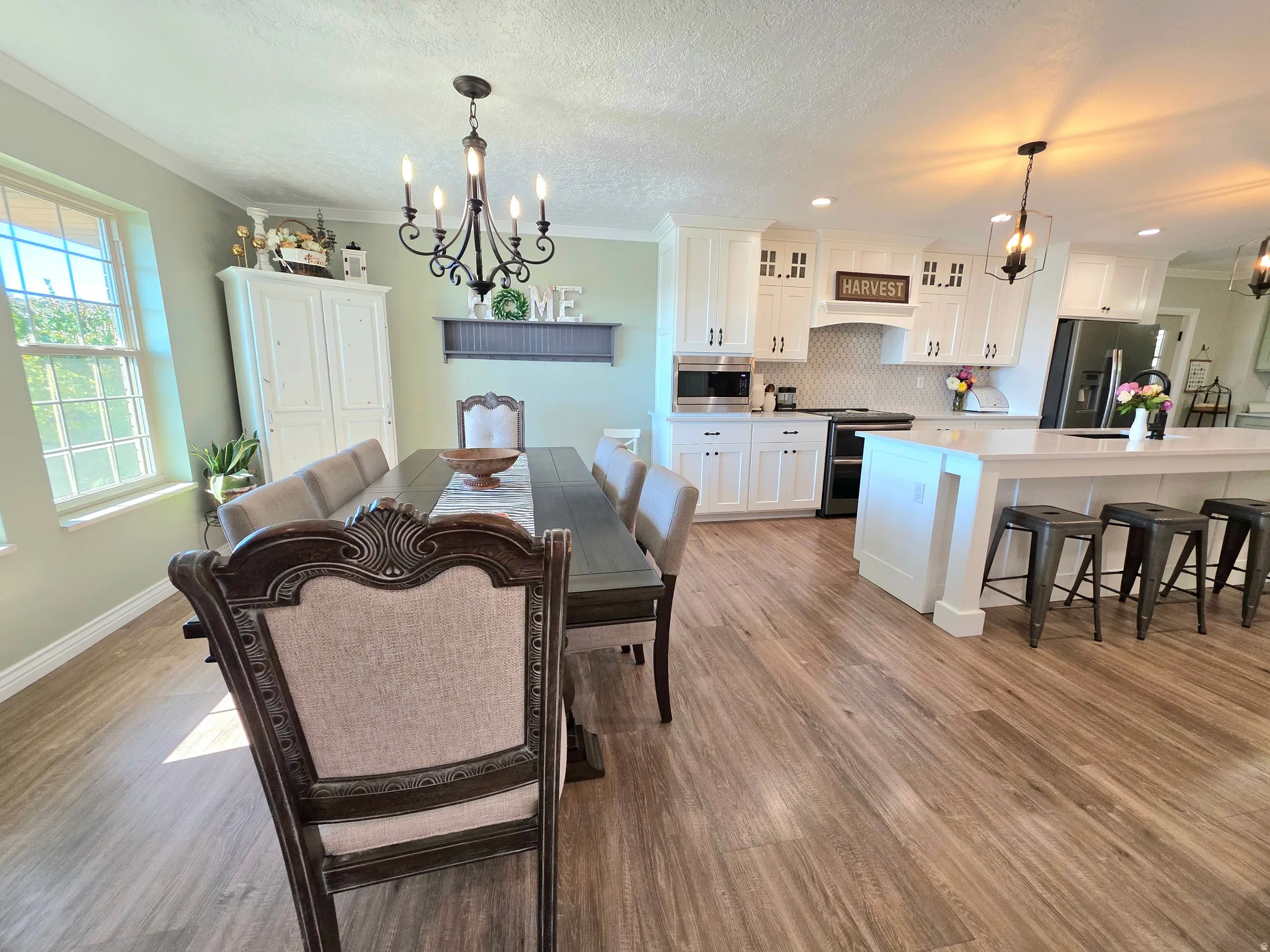 Dining space featuring a chandelier, ornamental molding, light wood finished floors, a textured ceiling, and recessed lighting