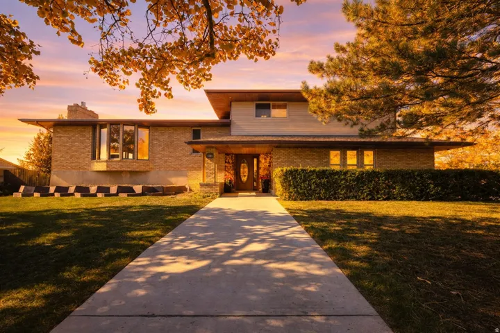 View of front facade featuring brick siding, a front yard, and a chimney