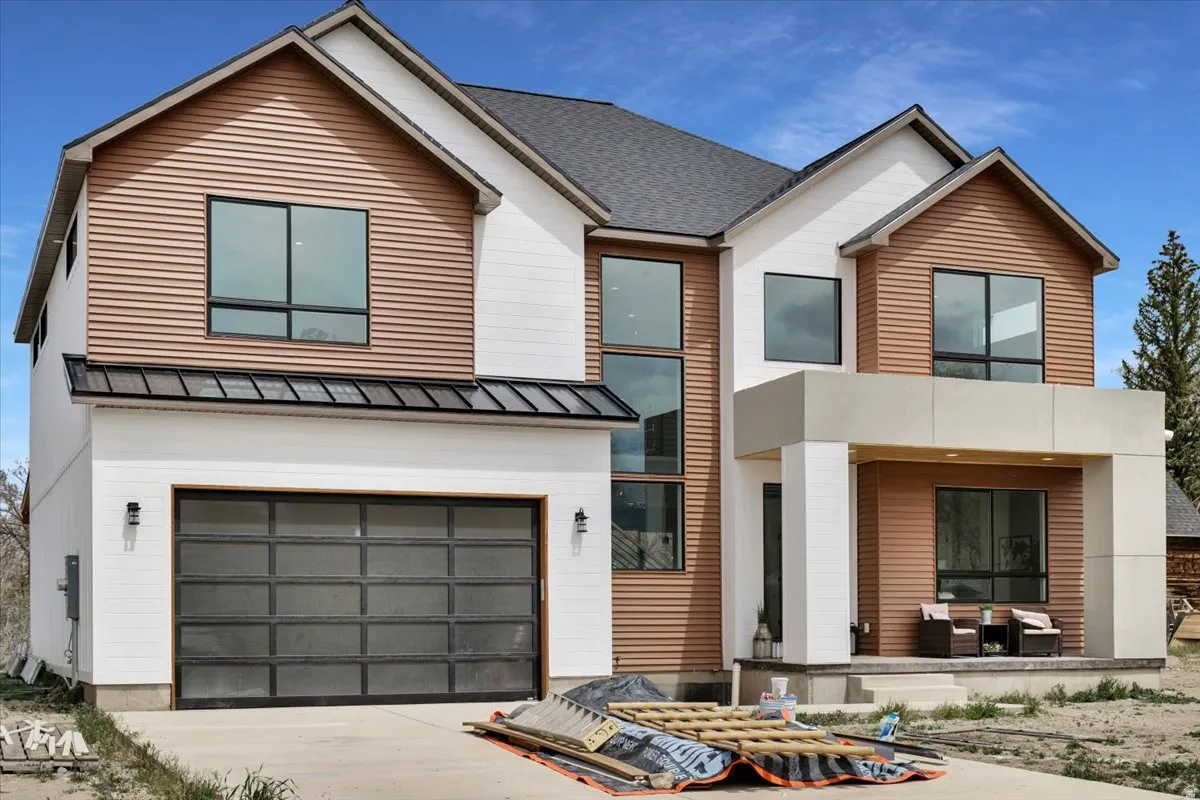 Contemporary house with a garage, a standing seam roof, driveway, and covered porch