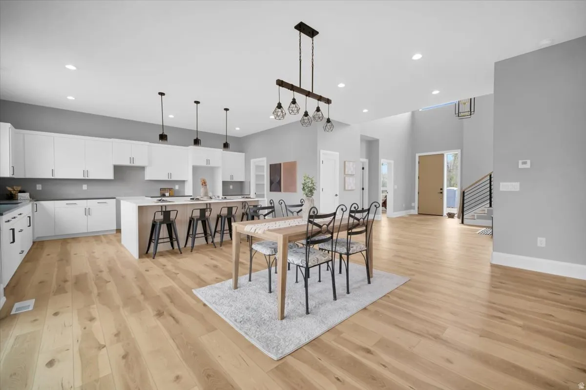 Dining space featuring a high ceiling, light wood-style floors, and recessed lighting