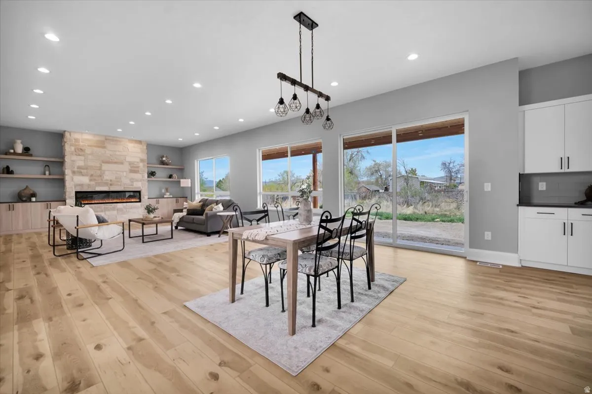 Dining area featuring a tile fireplace, light wood-type flooring, recessed lighting, and built in shelves