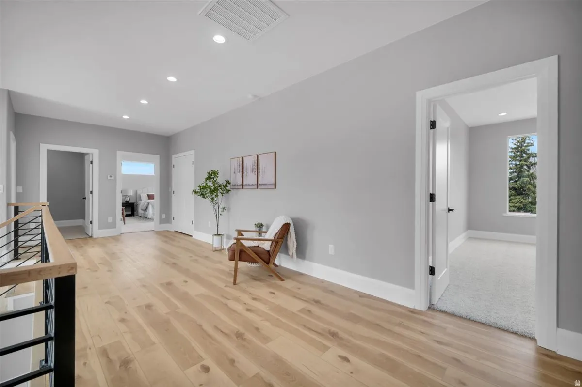 Living area with light wood-style flooring, an upstairs landing, and recessed lighting