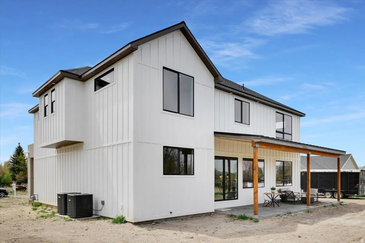 Back of house with a patio, board and batten siding, and roof with shingles