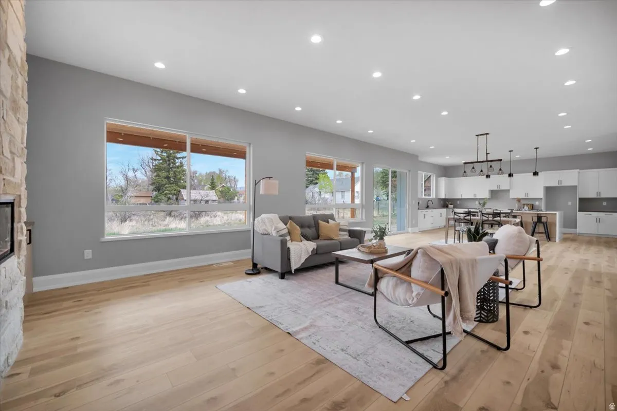 Living area with recessed lighting, light wood-style floors, and a stone fireplace