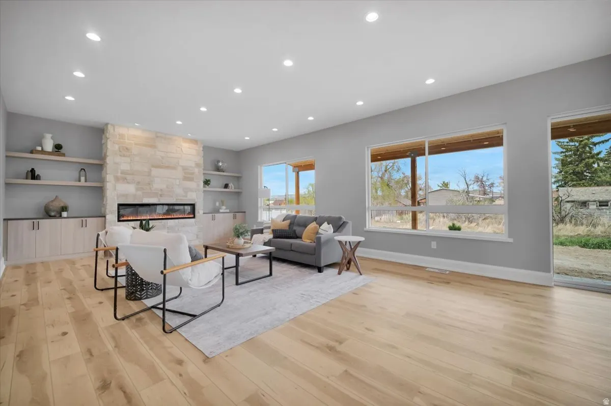Living room featuring recessed lighting, a fireplace, built in shelves, and light wood-style flooring