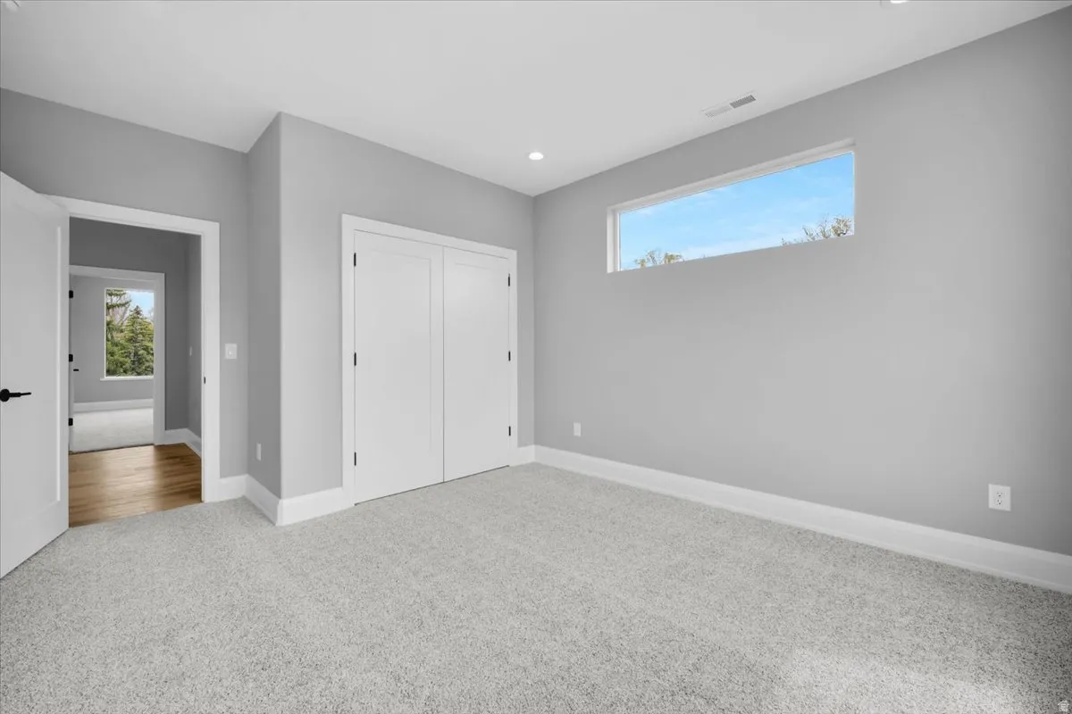 Unfurnished bedroom with light carpet, a closet, and recessed lighting