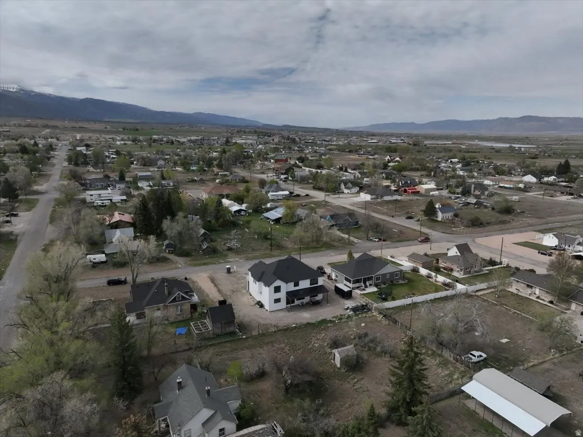 Aerial view of property and surrounding area with a mountainous background and nearby suburban area