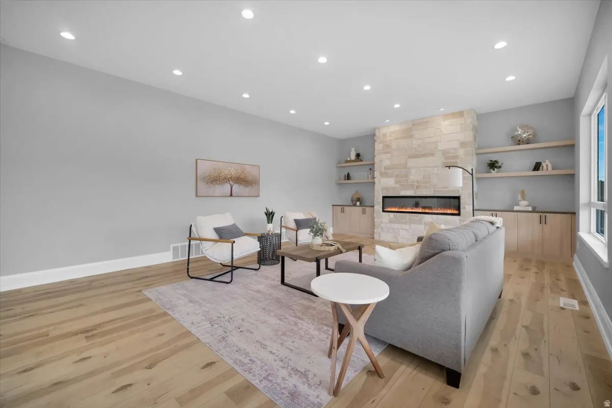 Living area with recessed lighting, light wood-style flooring, a fireplace, and built in shelves