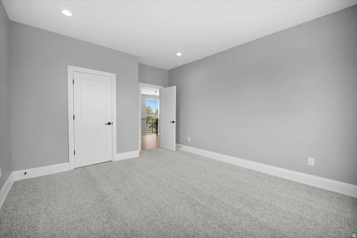 Unfurnished bedroom featuring light carpet, recessed lighting, and a closet