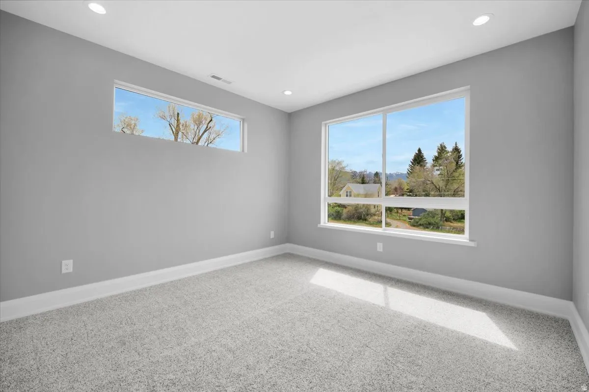 Empty room featuring light colored carpet, plenty of natural light, and recessed lighting