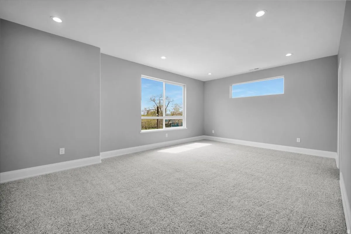 Empty room with light carpet and recessed lighting