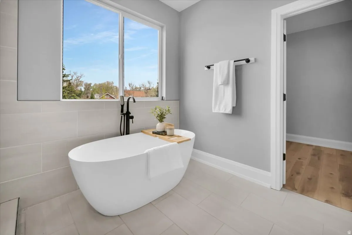 Bathroom featuring tile walls, a soaking tub, and tile patterned flooring