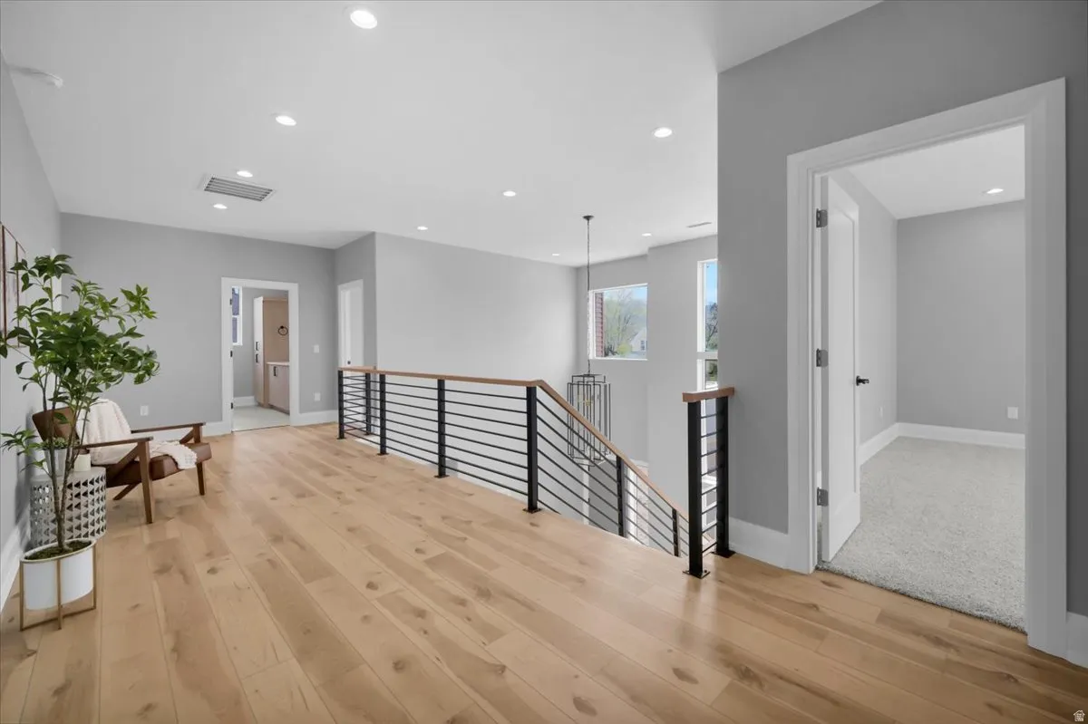 Hall with an upstairs landing, recessed lighting, and light wood-style floors