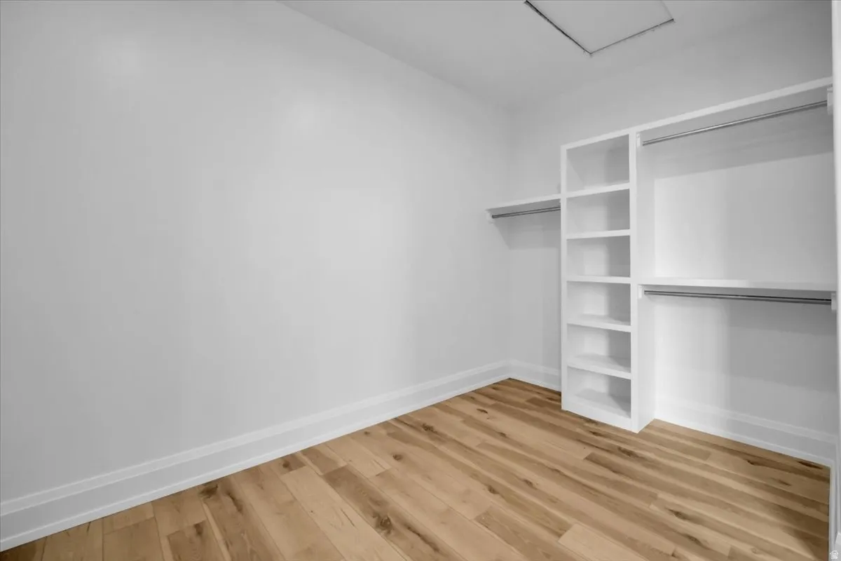 Walk in closet featuring light wood finished floors and attic access
