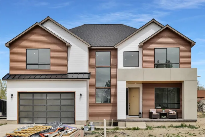 Contemporary home featuring a porch, a garage, a standing seam roof, and a shingled roof