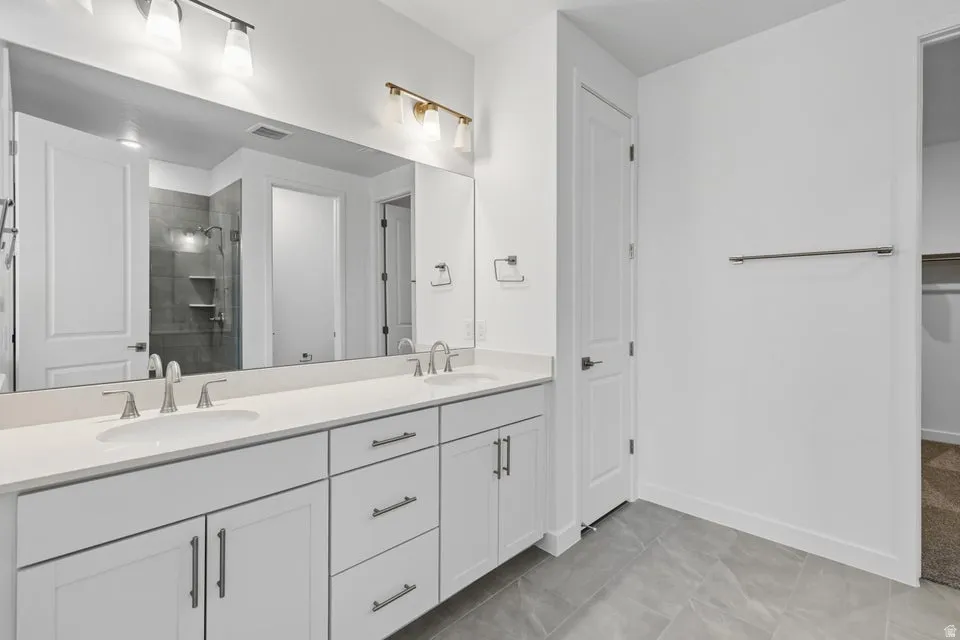 Bathroom with a shower stall, double vanity, a spacious closet, and light tile patterned flooring