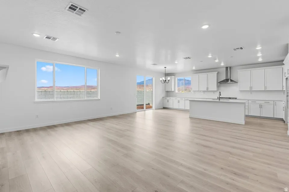 Unfurnished living room with light wood-type flooring, a chandelier, and recessed lighting