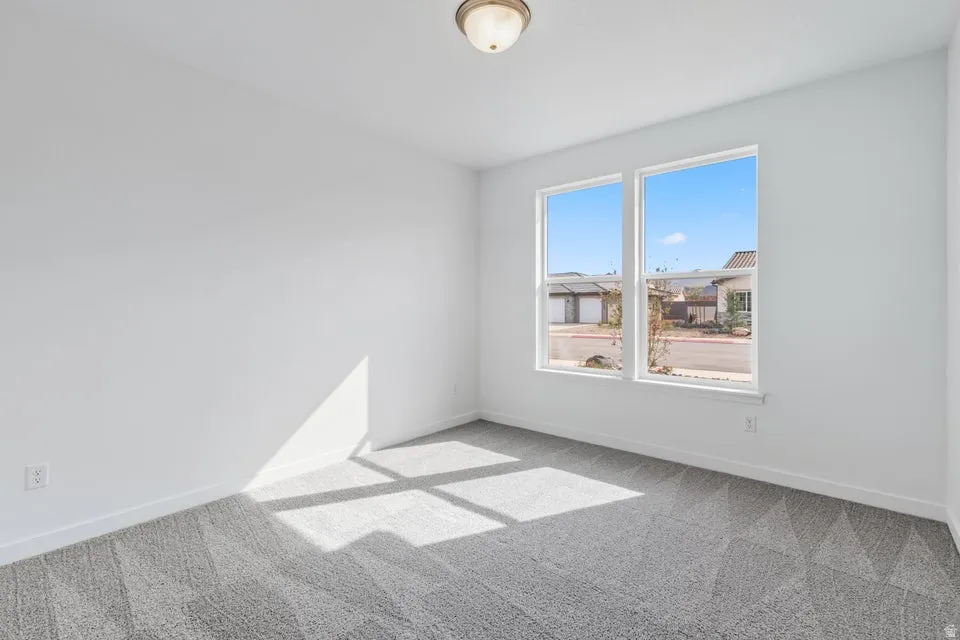 Empty room with light colored carpet and baseboards