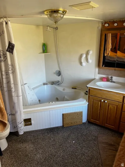 Bathroom featuring a combined bath / shower with jetted tub, vanity, ensuite bathroom, and dark carpet