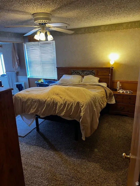 Bedroom featuring carpet flooring, a textured ceiling, and ceiling fan