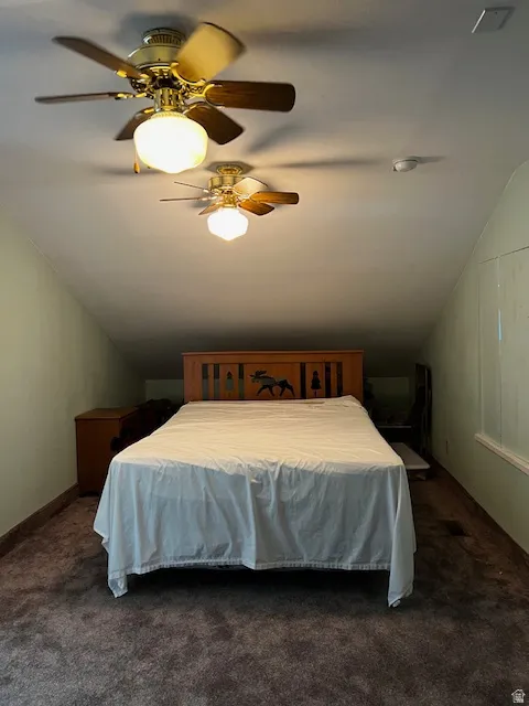 Bedroom featuring vaulted ceiling, ceiling fan, and dark carpet