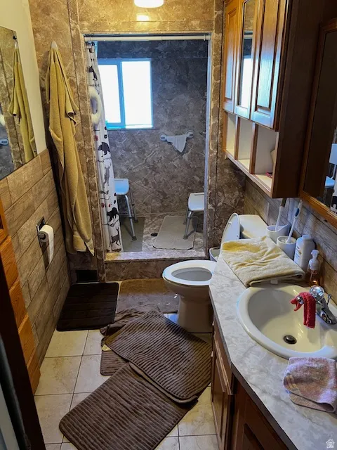 Bathroom with vanity, light tile patterned floors, a tile shower, and tile walls