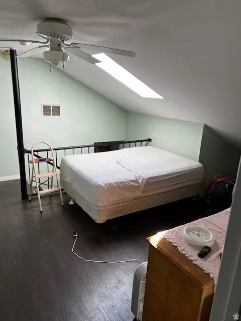 Bedroom featuring lofted ceiling, a skylight, dark wood finished floors, and a ceiling fan