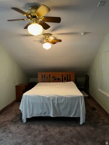 Bedroom featuring vaulted ceiling, ceiling fan, and dark carpet