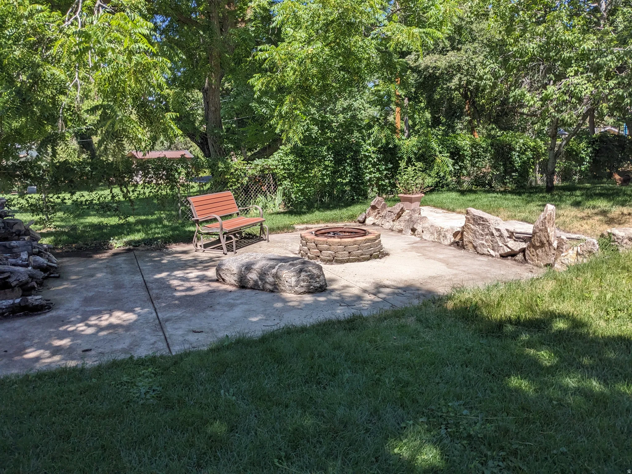 View of grassy yard with a patio and an outdoor fire pit