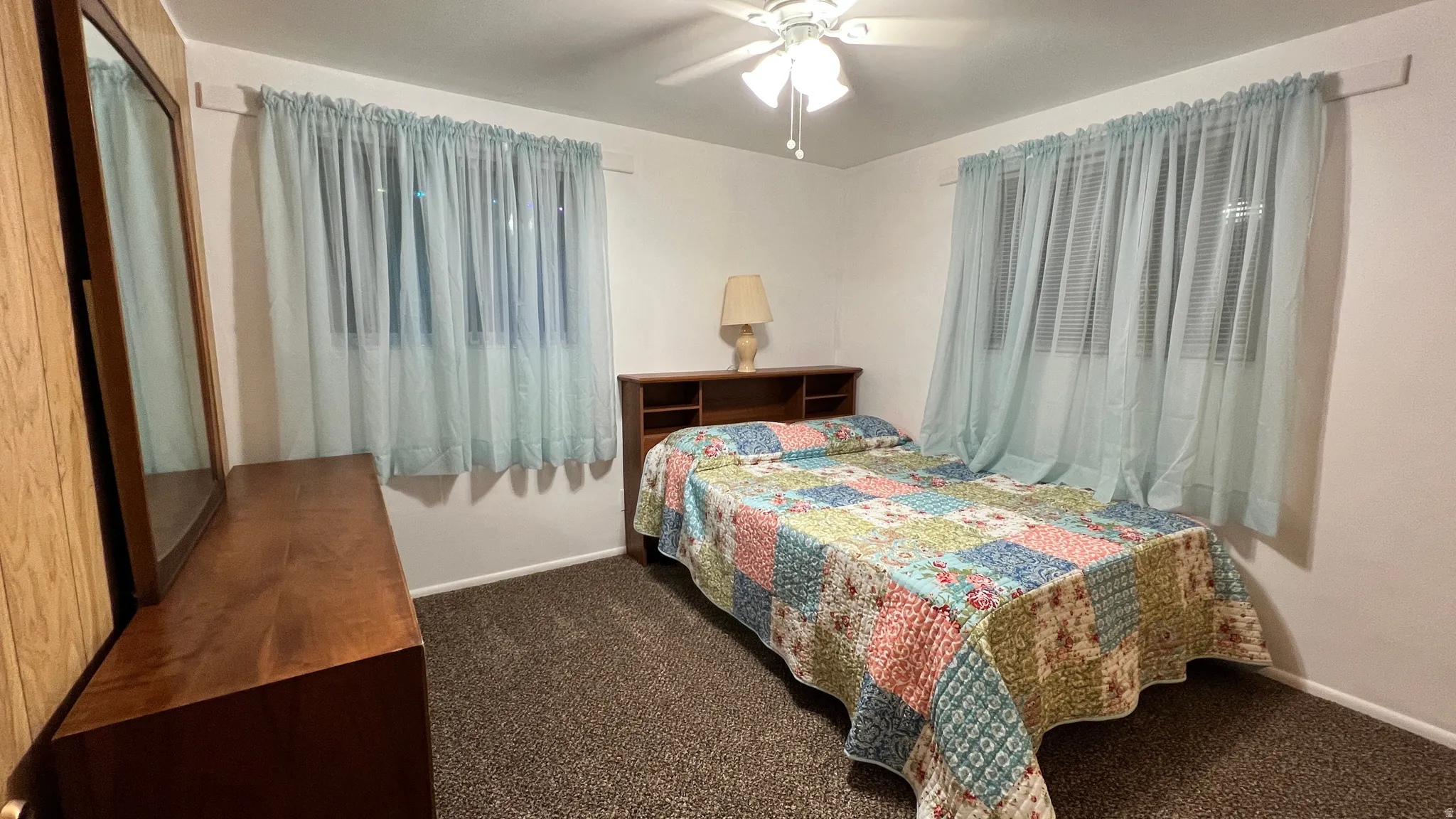 Carpeted bedroom featuring ceiling fan and baseboards