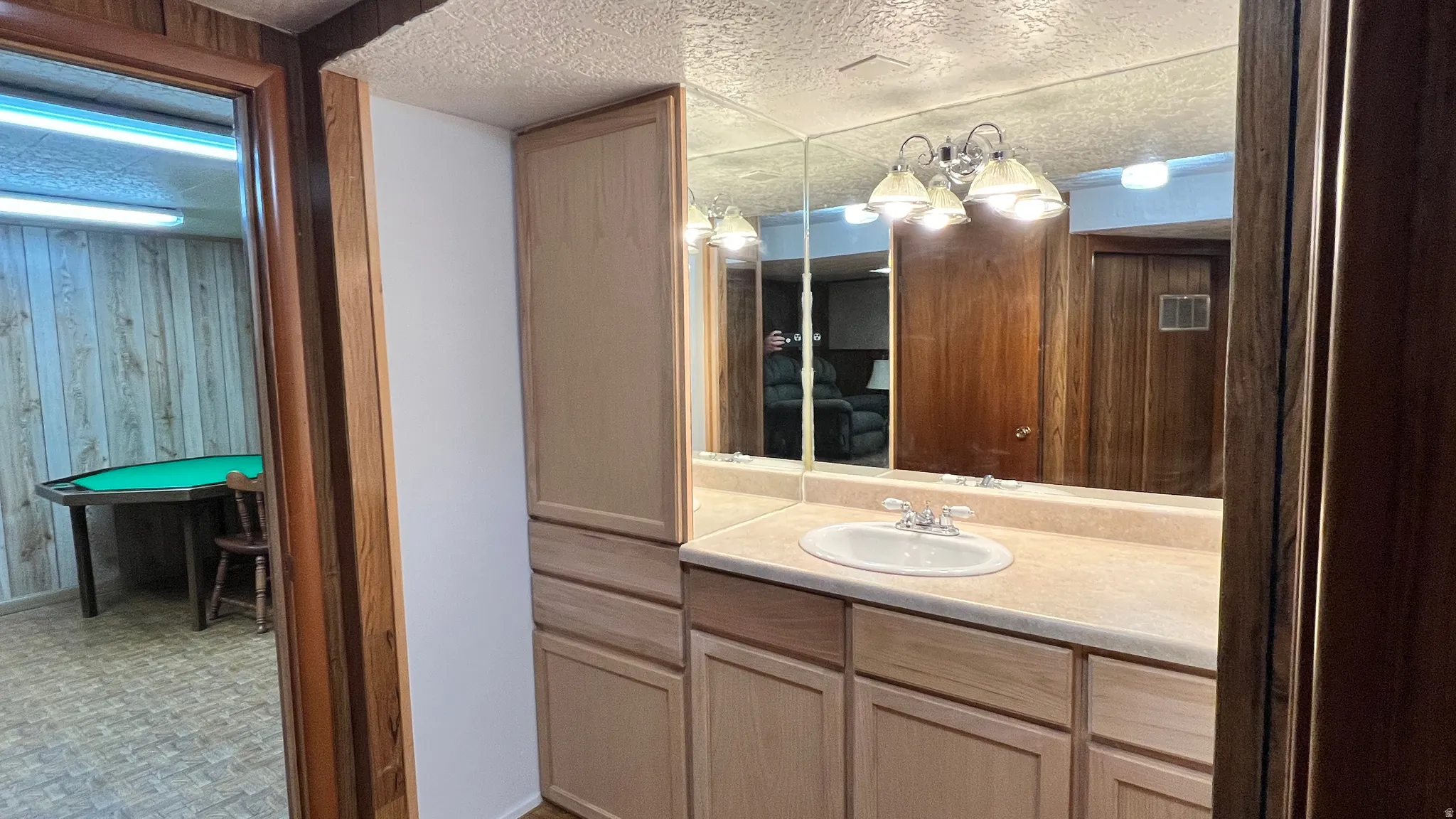 Bathroom with vanity, a textured ceiling, wood walls, and tile patterned floors