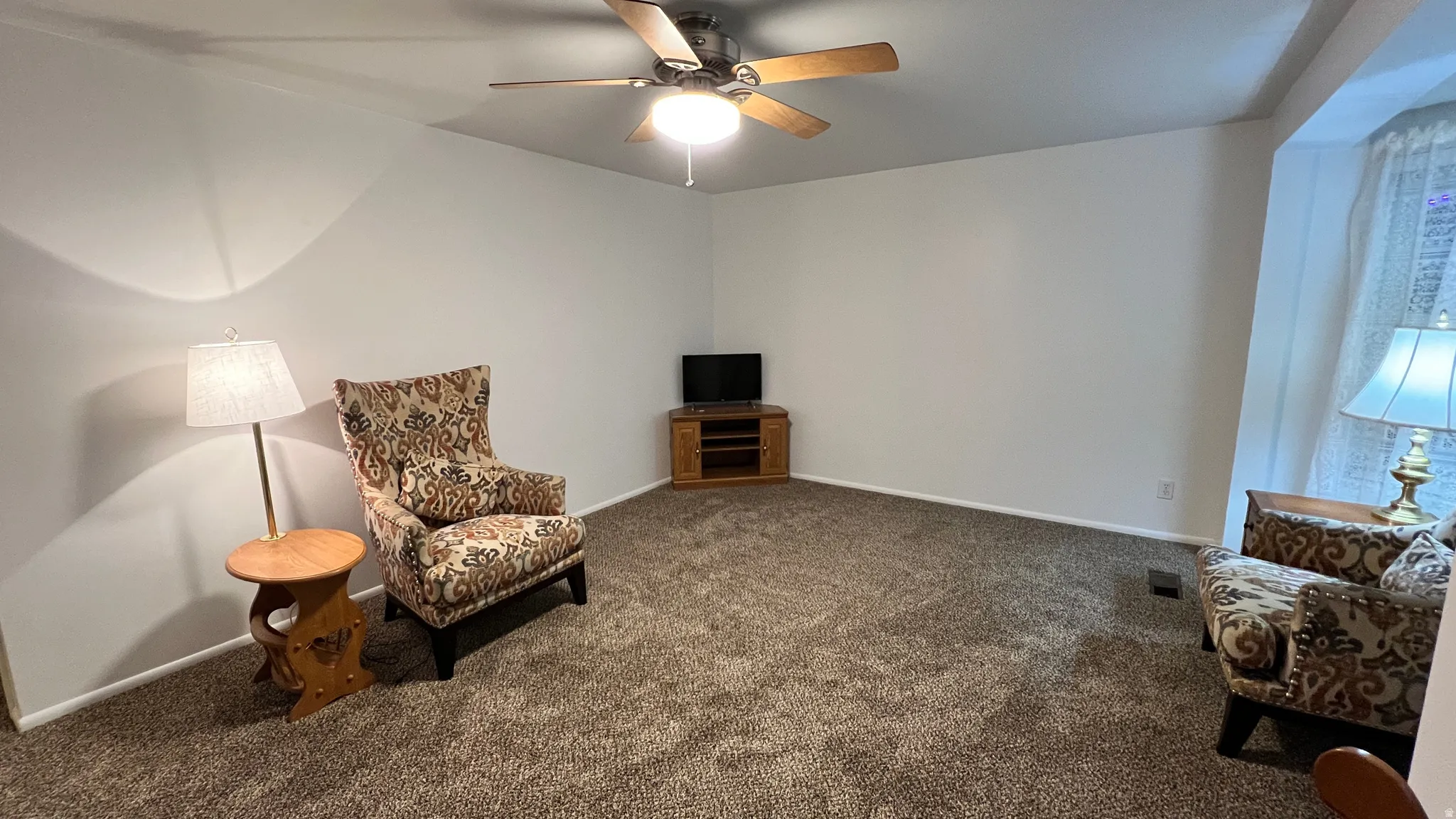 Living area featuring carpet and a ceiling fan