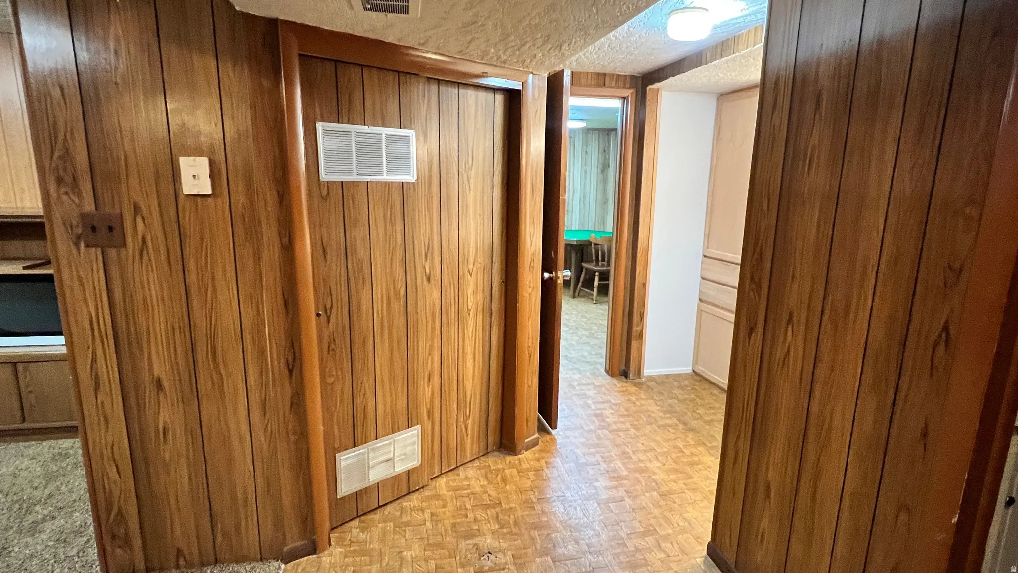 Corridor featuring wooden walls and a textured ceiling